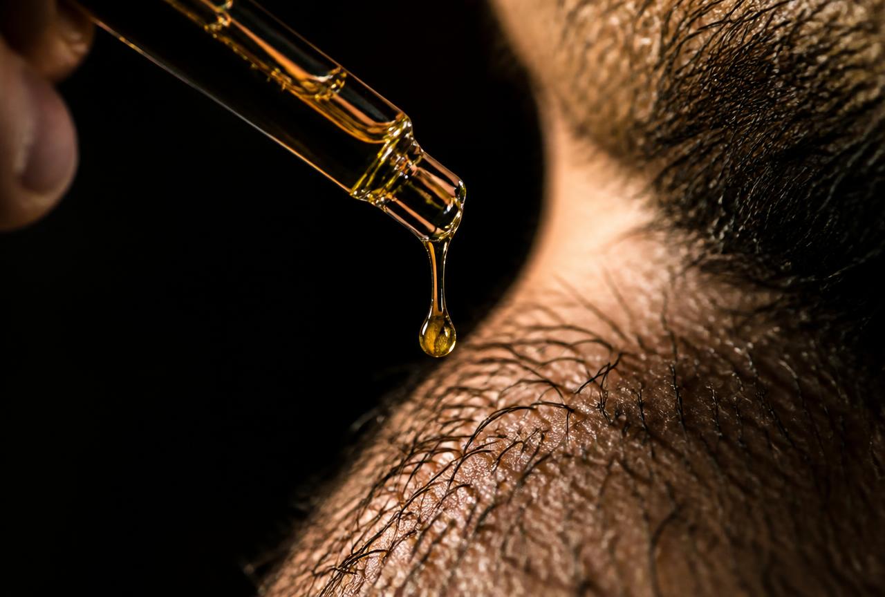 Goutte d'huile à barbe tombant sur la peau sous les poils